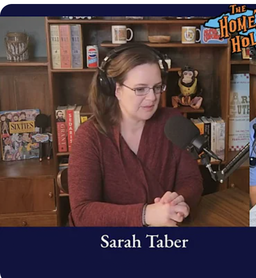 Sarah Taber sitting at a table, speaking into a microphone